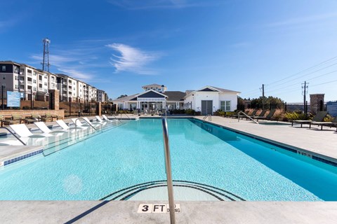 a swimming pool with white chairs and a building in the background at Capstone at Banks Crossing, Commerce