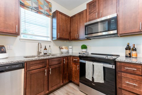 a kitchen with wooden cabinets and a stove and microwave at Capstone at Banks Crossing, Commerce