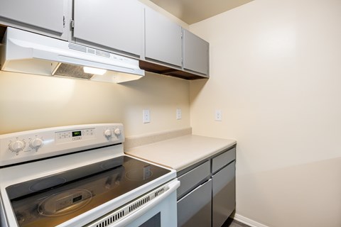 A white stove and oven in a kitchen with white cabinets.