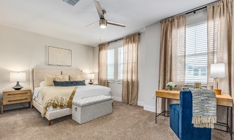 A bedroom with a bed, a chair, and a table.