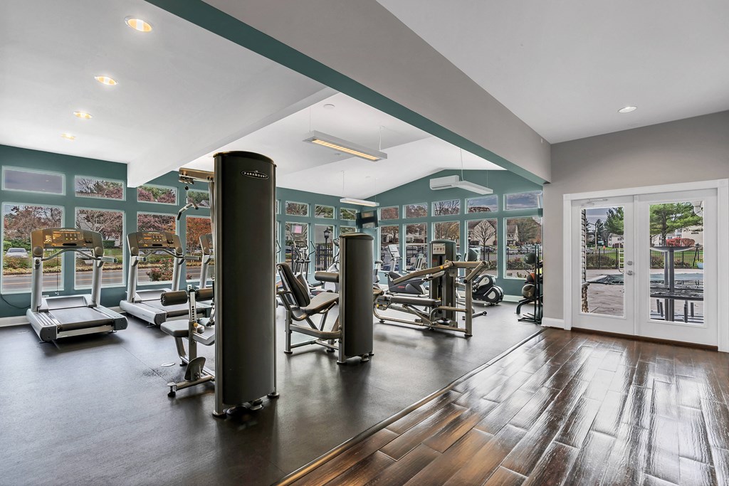 a gym with exercise equipment and a glass door with a view of a parking lot at Misty Ridge Apartments, Woodbridge, VA