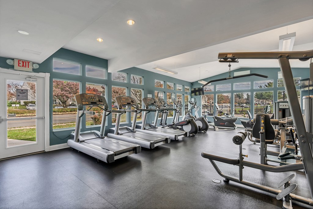 a gym with cardio equipment and windows with a view of the street at Misty Ridge Apartments, Virginia