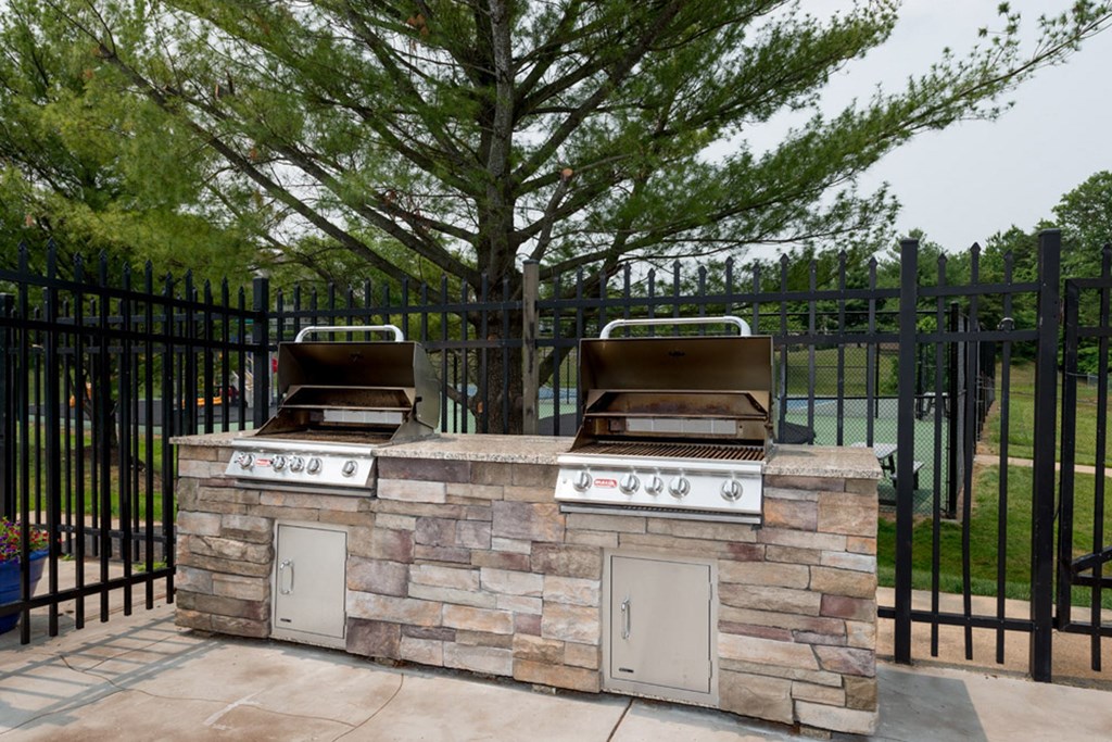 an outdoor kitchen with a grill and a tree in the background at Misty Ridge Apartments, Woodbridge