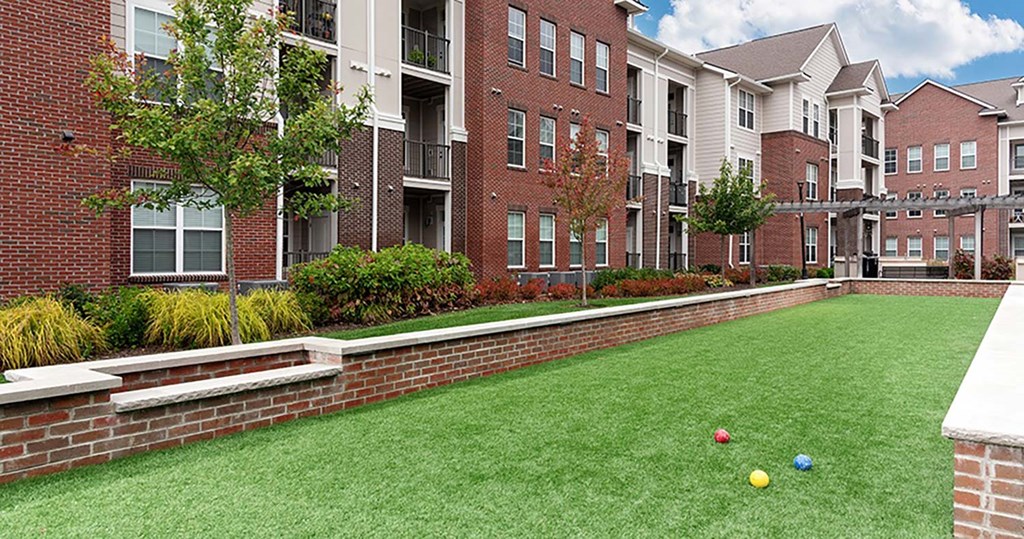 a grassy area with bocce balls in front of a brick building at Canopy at Ginter Park Apartments, Richmond, VA, 23227