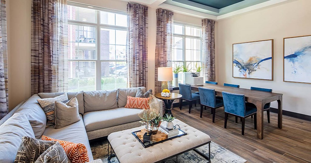 a living room with a large window and a long wooden table with blue chairs at Canopy at Ginter Park Apartments, Richmond, VA, 23227