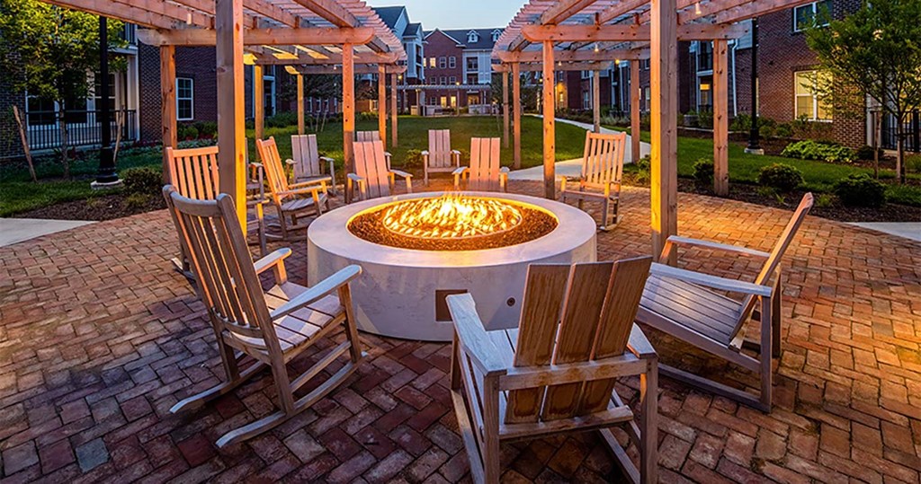 a fire pit in the middle of a brick patio with wooden chairs and a pergola at Canopy at Ginter Park Apartments, Richmond, VA, 23227