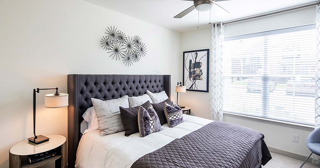 a bedroom with a large window and a ceiling fan