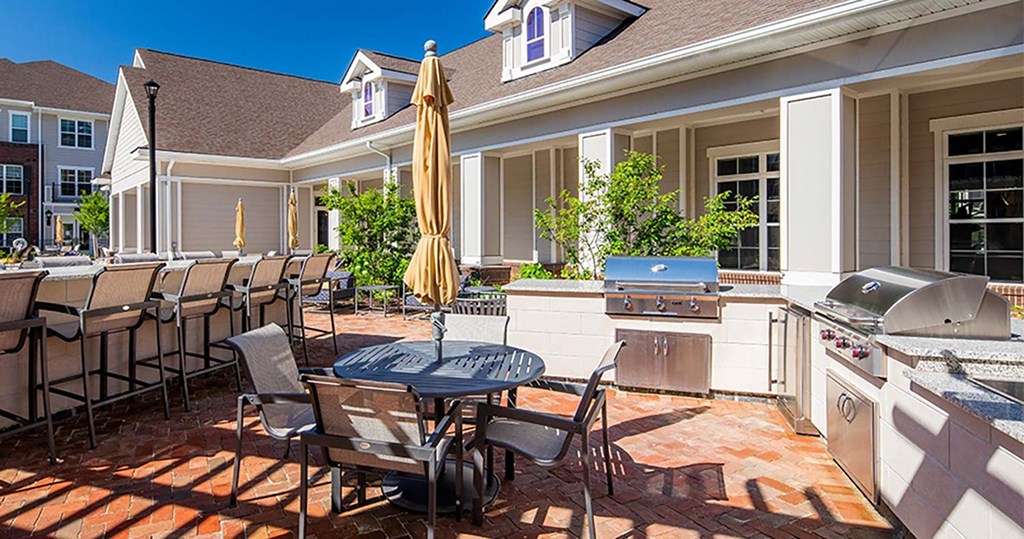 a patio with a grill and a table and chairs