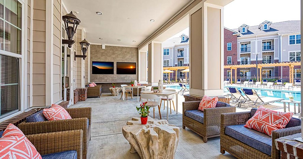 a patio with wicker furniture and a pool in the background