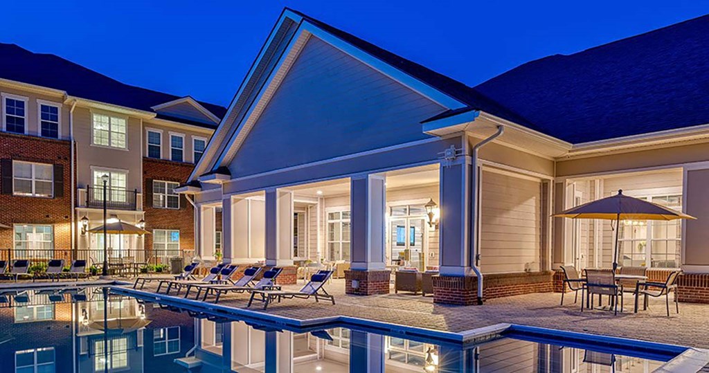 a swimming pool with chaise lounge chairs and an umbrella in front of a building