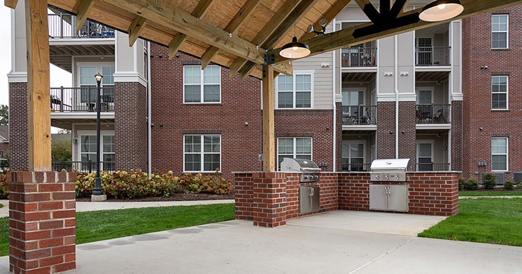 a patio with a grill and barbecue in front of an apartment building