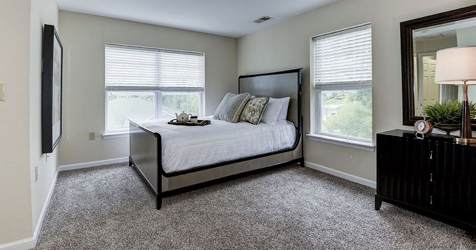a bedroom with a bed and two windows at SomerHill Farms Apartments, Gainesville Virginia