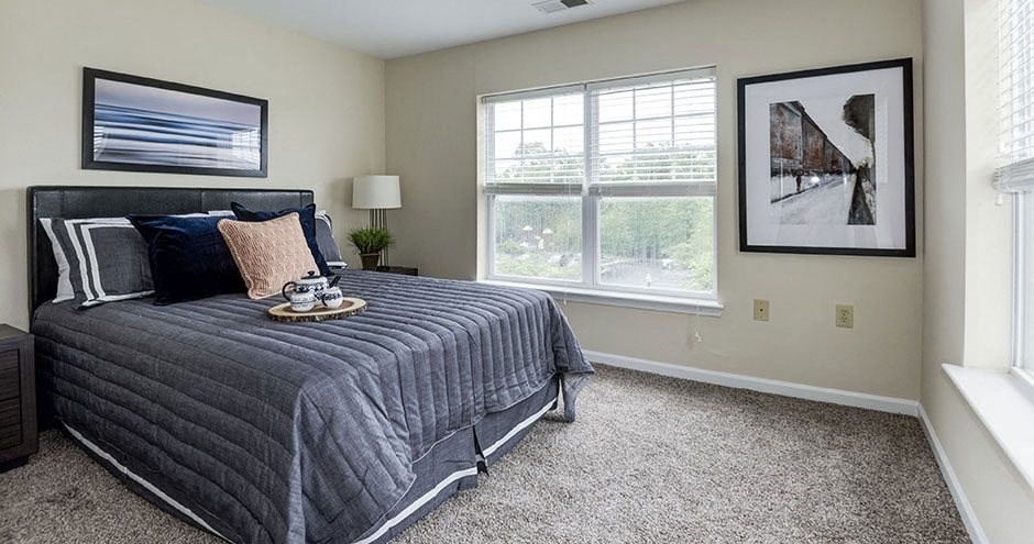 a bedroom with a large bed and two windows at SomerHill Farms Apartments, Gainesville