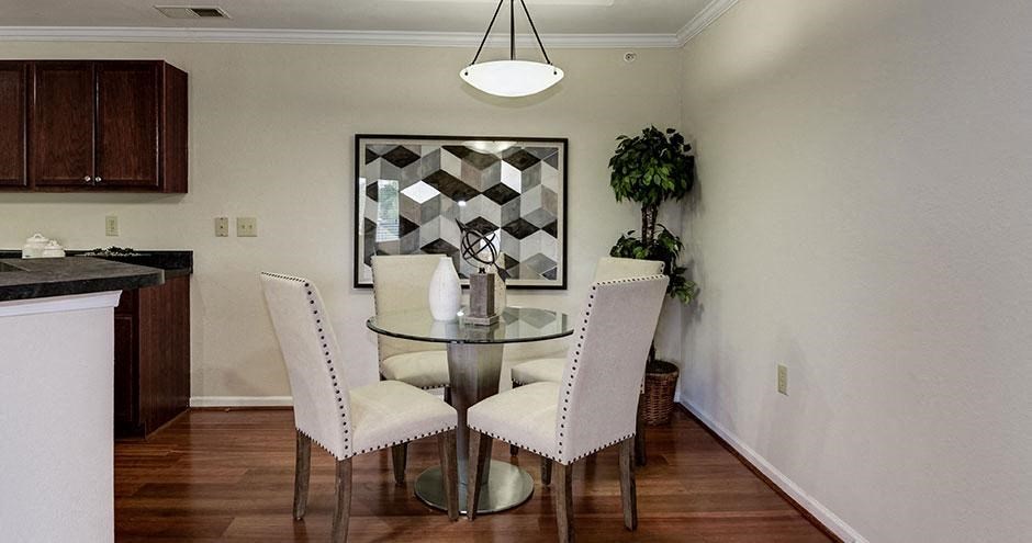 a dining room with a glass table and white chairs at SomerHill Farms Apartments, Gainesville Virginia