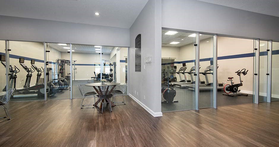 a gym with a table and chairs in the middle of the room at Bellemeade Farms Apartments, Leesburg Virginia