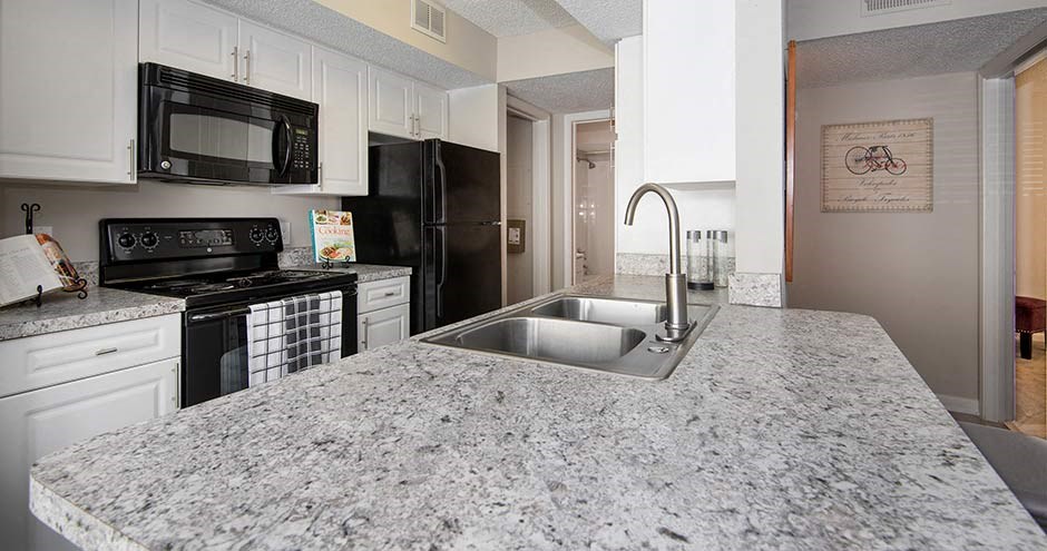 a kitchen with a sink a stove and a microwave at Bellemeade Farms Apartments, Leesburg