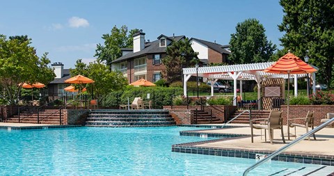 a pool with chairs and umbrellas and a building in the background at Bellemeade Farms Apartments, Virginia