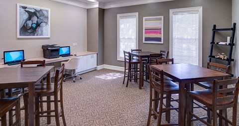 A room with a dining table and chairs, a computer desk with two monitors, and a bookshelf at Austin Chase Apartments, Macon, Georgia
