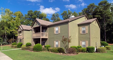 A green two story apartment building with a balcony on the second floor at Austin Chase Apartments, Macon, Georgia