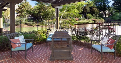 A patio with a fireplace and two chairs at Austin Chase Apartments, Macon, GA