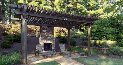 A patio with a fireplace and chairs under a wooden pergola at Austin Chase Apartments, Macon, GA