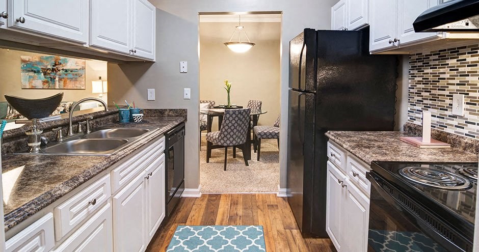 A kitchen with a black refrigerator and a table with chairs in the middle A kitchen with a black refrigerator and a table with chairs in the middle at Austin Chase Apartments, Georgia 31210