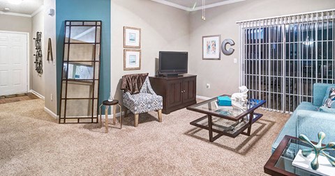 A living room with a couch, chair, and television at Austin Chase Apartments, Macon, GA