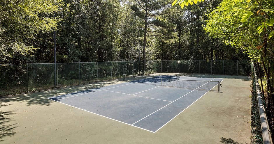 A tennis court surrounded by a fence and trees.