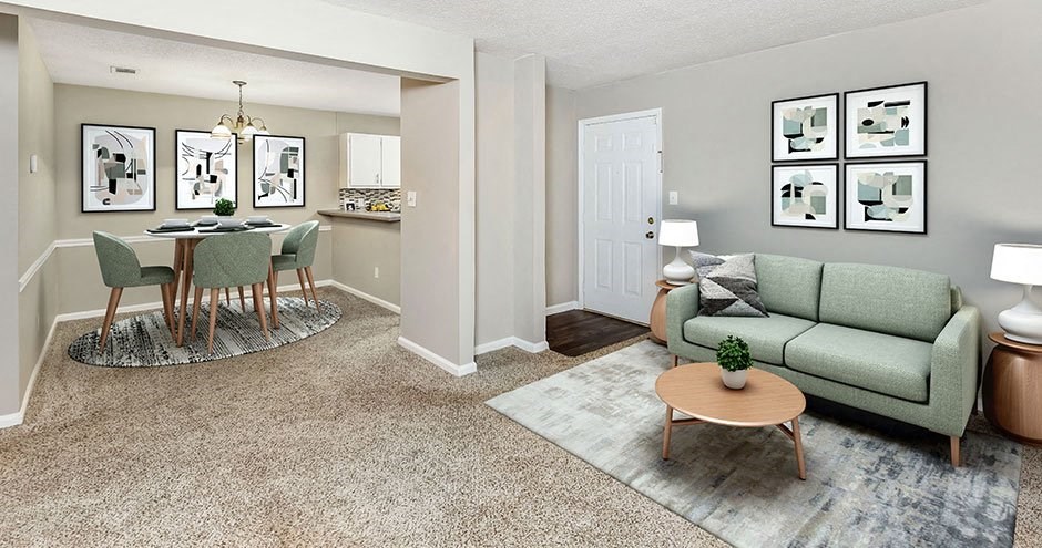 A living room with a green couch and a dining table with chairs.
