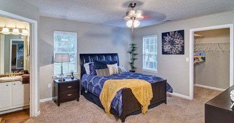 A bedroom with a bed, nightstand, and a ceiling fan at Huntington Chase Apartments, Warner Robins