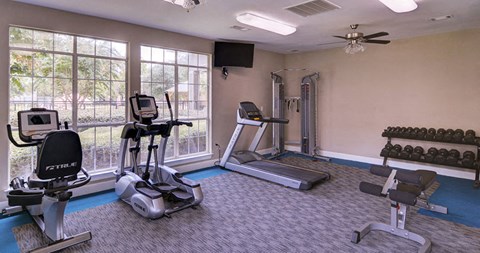 A home gym with a treadmill, elliptical trainer, and a rowing machine at Huntington Chase Apartments, Warner Robins, 31088