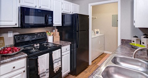 A kitchen with black appliances and white cabinets at Huntington Chase Apartments, Warner Robins, GA