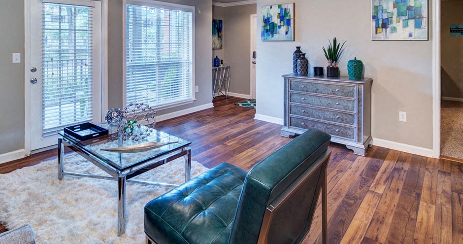 A living room with a black leather chair and a glass coffee table A living room with a black leather chair and a glass coffee table at Huntington Chase Apartments, Warner Robins, GA 31088
