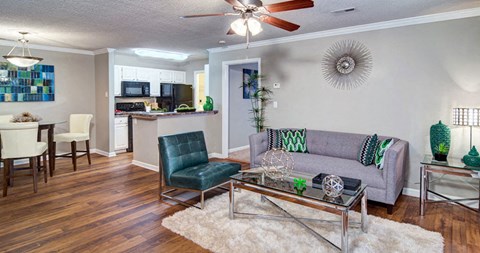 A living room with a grey couch and a glass coffee table.
