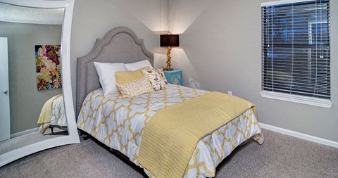 A bed with a yellow comforter and pillows sits in a room with a grey headboard at Southland Station Apartments, Warner Robins, Georgia, 31088