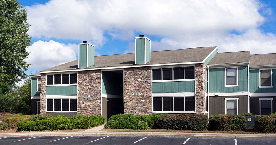 A large building with a green roof and a stone pillar in front at Southland Station Apartments, Warner Robins, Georgia