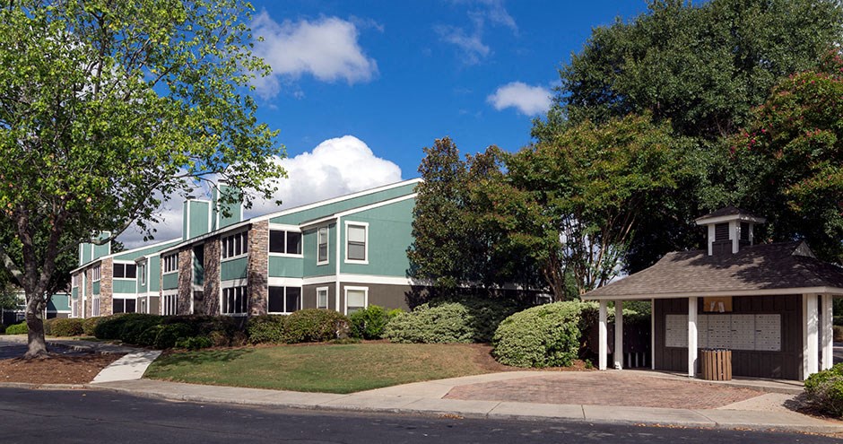 A green and white building with a gazebo-like structure in front at Southland Station Apartments, Warner Robins, Georgia