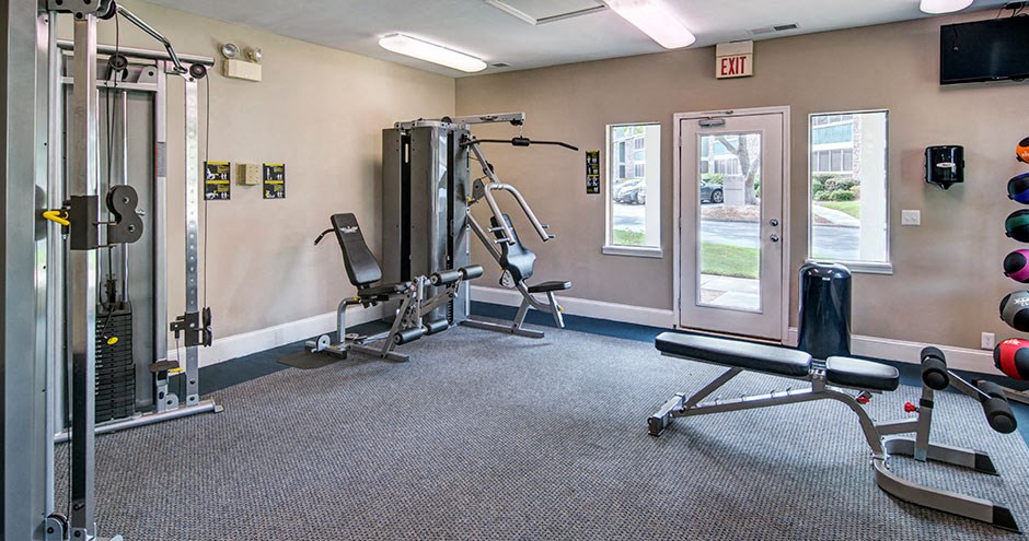 A gym with a variety of equipment including a squat rack, a leg press machine, and a bench press at Southland Station Apartments, Warner Robins, 31088