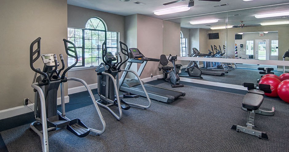 A gym with treadmills, elliptical machines, and other exercise equipment.