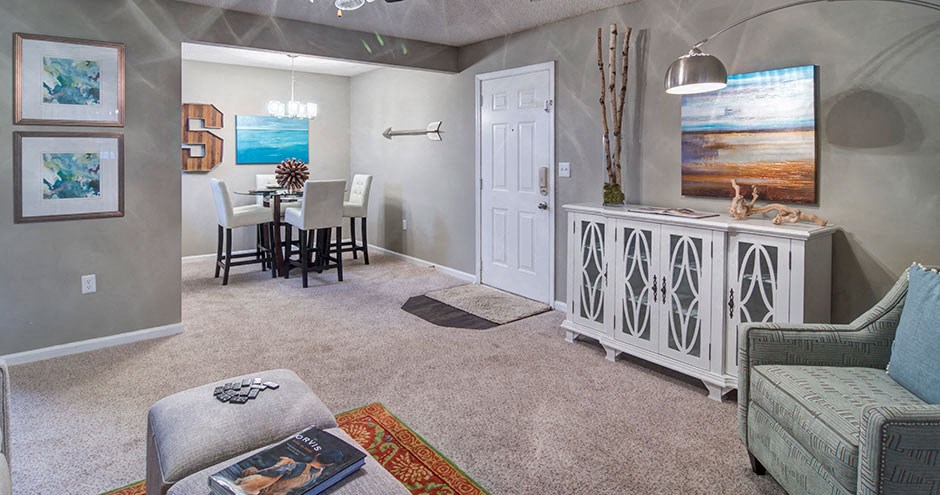 A living room with a grey couch, a white cabinet, and a painting on the wall.