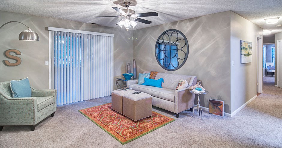 A living room with a sofa, armchair, and a rug at Southland Station Apartments, Warner Robins, 31088