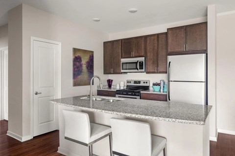 A kitchen with a granite countertop and white chairs.