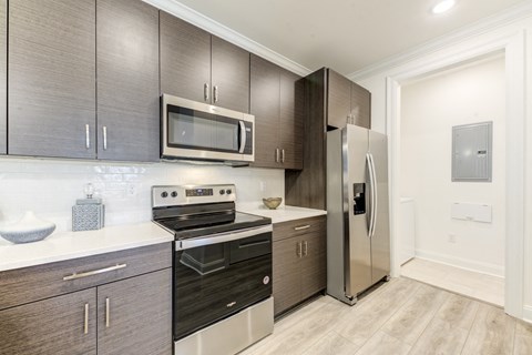 a modern kitchen with stainless steel appliances and dark wood cabinets at Residences at 393 North Apartments, Santa Rosa Beach, FL