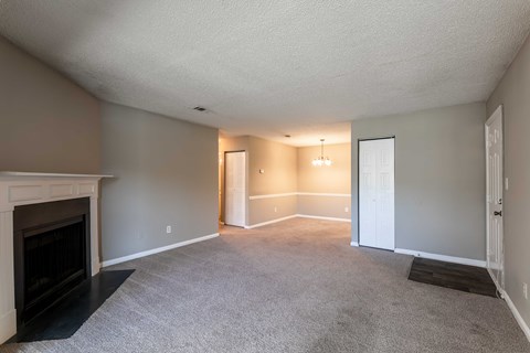 A living room with a fireplace and carpeted floor.