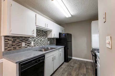 A kitchen with black appliances and white cabinets.