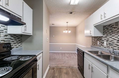 A kitchen with a black stove top oven and white cabinets.