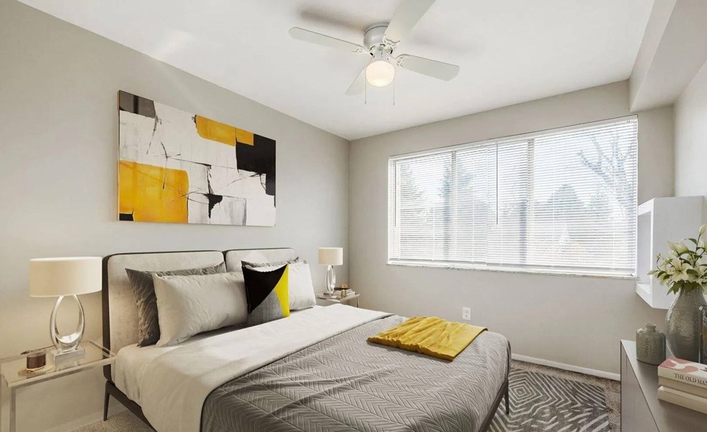 A bedroom with a bed, a ceiling fan, and a painting on the wall.