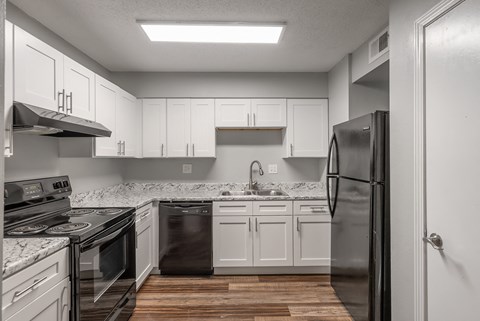 A kitchen with white cabinets and a black refrigerator.