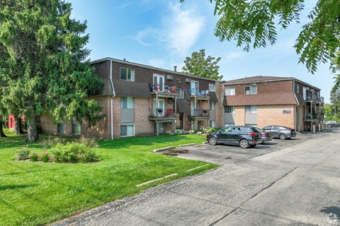 A row of houses with cars parked in front.