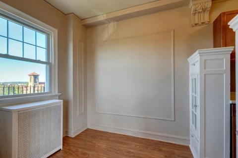A room with a window, a radiator, and a white wardrobe.